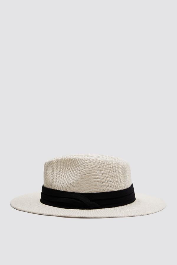 Este sombrero trenzado en color blanco se convertirá en tu mejor aliado para los días de sol. De ala ancha y detalle de cinta en color negro, es de Zara y tiene un precio de 22,95 euros. Está disponible en la talla S y la M.
