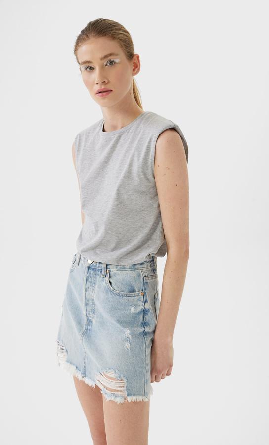 En gris mezcla, con cuello redondo y manga sisa, esta camiseta de Stradivarius cuesta 9,99 euros y está disponible entre las tallas XS y L.