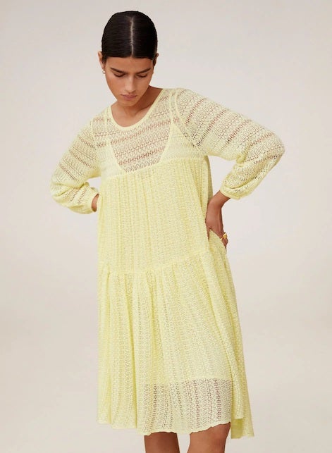 Vestido acampanado de punto calado con mangas abullonadas en tono amarillo pastel. (59,99 euros).