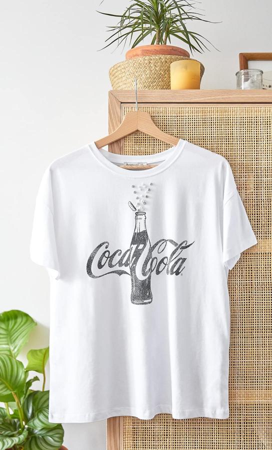 Para las que quieren ir cómodas mientras presumen de las nuevas prendas de su armario de temporada, esta camiseta de Stradivarius con abalorios a modo de espuma de la Coca Cola es perfecta. Está disponible entre las tallas XS y L y cuesta 15,99 euros.