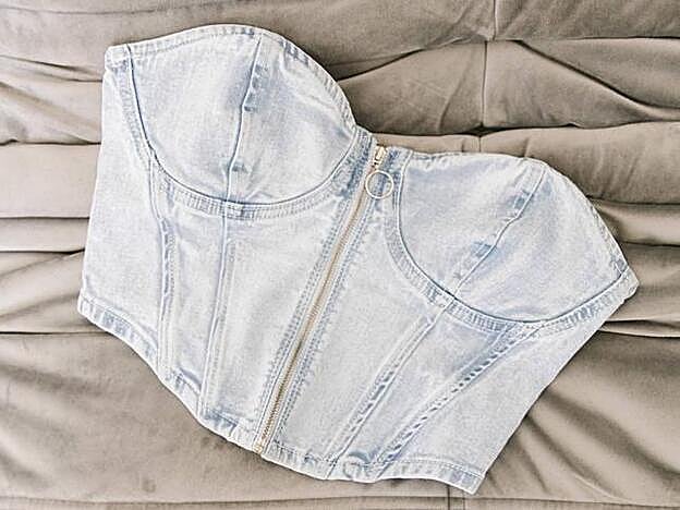 El top corsé confeccionado en tejido vaquero de Bershka cierra con cremallera.