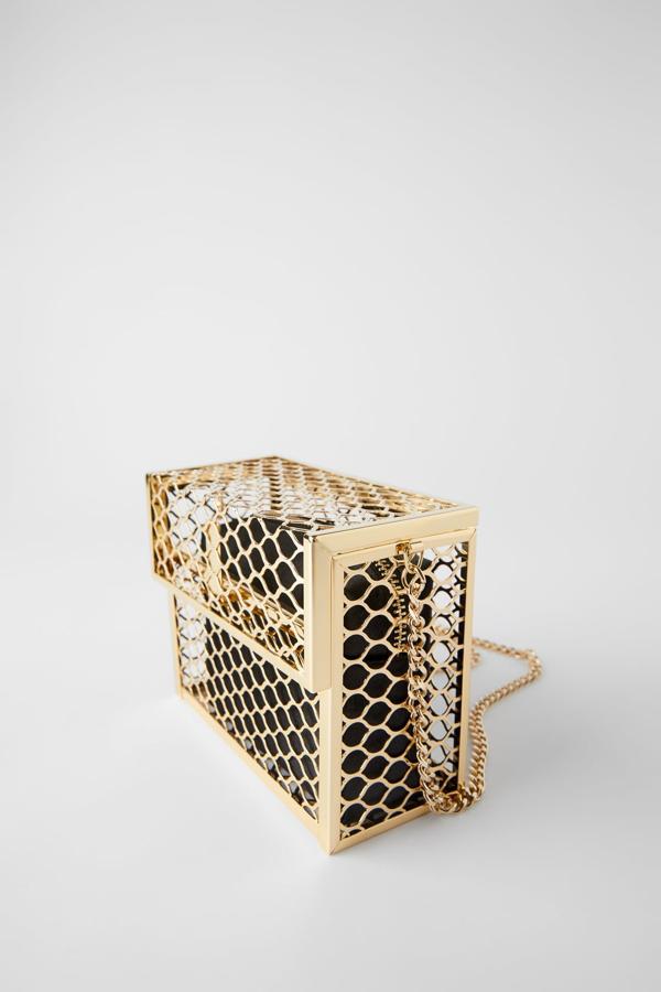 Con cuerpo de panel metálico en color dorado e interior extraíble en contraste con acabado satinado y cierre de cremallera, este bolso de mano es de Zara. El cuerpo tiene cierre media