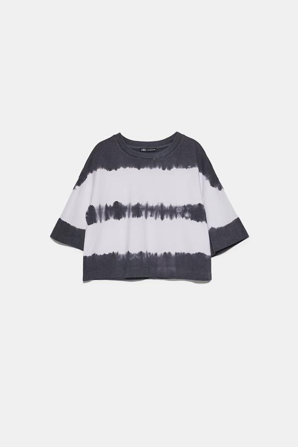 Con el estampado más veraniego y hippie de la temporada, esta camiseta de Zara tie dye en blanco y negro viene con cuello redondo y manga corta a la altura del codo. Confeccionada en algodón orgánico, cuesta 9,95 euros y está disponible entre las tallas S y L.