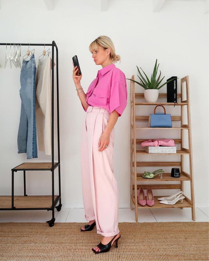 Un total look en rosa pero en dos tonos diferentes: una camisa fucsia y unos pantalones pastel. Rompen con el monocolor unas sandalias negras.