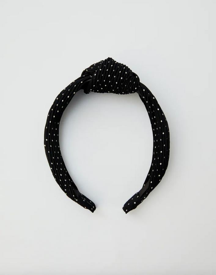 Otra propuesta en color negro es esta diadema con topos blancos y nudo en la parte superior. Es de Pull&Bear, cuesta 4,99 euros y se está agotando.