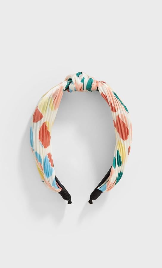 Si tienes en tu armario un montón de prendas en tonos pastel esperando a ser estrenadas, no se nos ocurre mejor complemento para tu melena que esta diadema de Stradivarius. Plisada y con un estampado de círculos en tonos pastel, cuesta 5,99 euros.