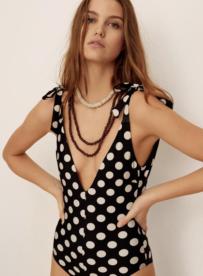 Mango lleva los lunares hasta su colección de baño. Con lazos en los hombros, este escotado bañador negro con lunares blancos tiene un precio de 39,99 euros.