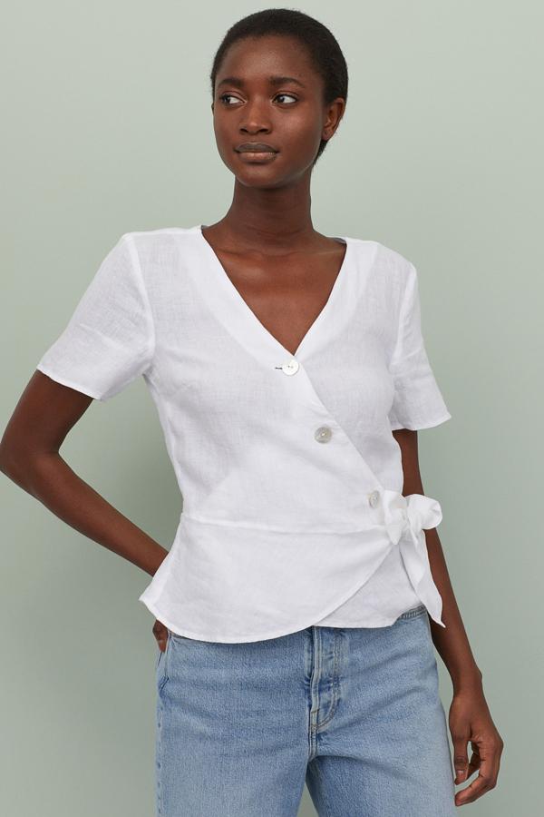Esta blusa de lino cruzada en color blanco es de lo más favorecedora. De manga corta y escote de pico, cuenta con botones delanteros y lazada. Tiene un precio de 19,99 euros.
