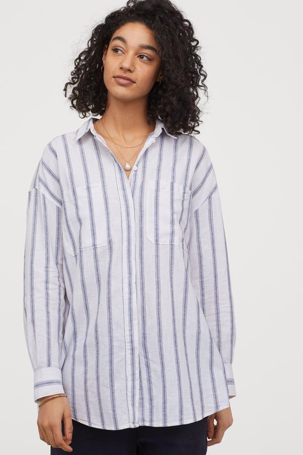 Esta camisa larga de lino con rayas en azul oscuro, también está disponible en blanco o en verde liso. Con hombros caídos y botones ocultos, tiene un precio de 29,99 euros.