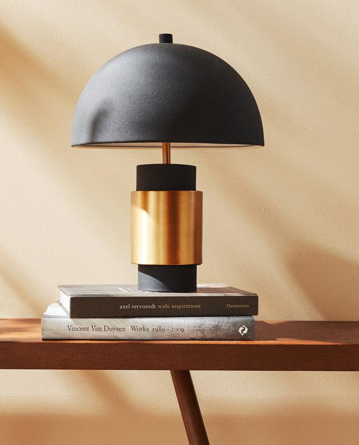 En Zara Home encontramos esta lámpara de mesa con base y pantalla de metal bicolor en dorado y negro. Tiene un precio de 79,99 euros.