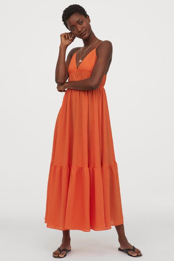 Uno de los tonos de la temporada es el naranja, y nos encanta en esta versión de H&M en tejido vaporoso con textura. Con escote de pico y costura fruncida bajo el busto, cuesta 49,99 euros y solo queda, y pocos, en las tallas 40 y 42.