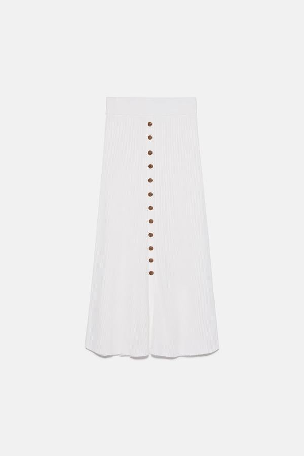 Confeccionada en punto con cintura elástica y tiro alto, esta bonita falda blanca de Zara viene con detalle de botones en delantero. Cuesta 29,95 euros y está disponible entre las tallas S y L.