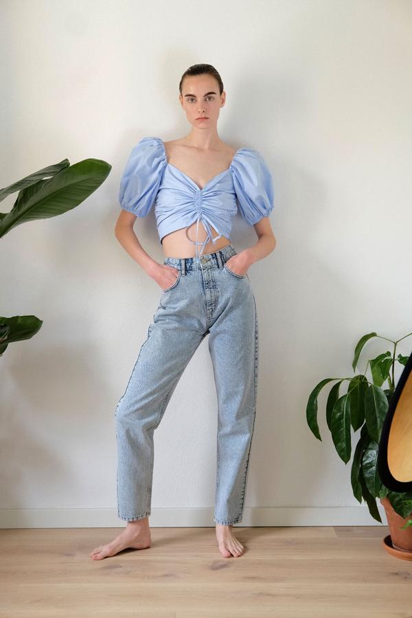 Este bonito top en azul cielo de Sfera tiene un precioso fruncido en el centro del delantero, ideal para las que pueden presumir de figura, y las mangas abullonadas. Tiene un precio de 29,99 euros y está disponible en las tallas S, M y L.