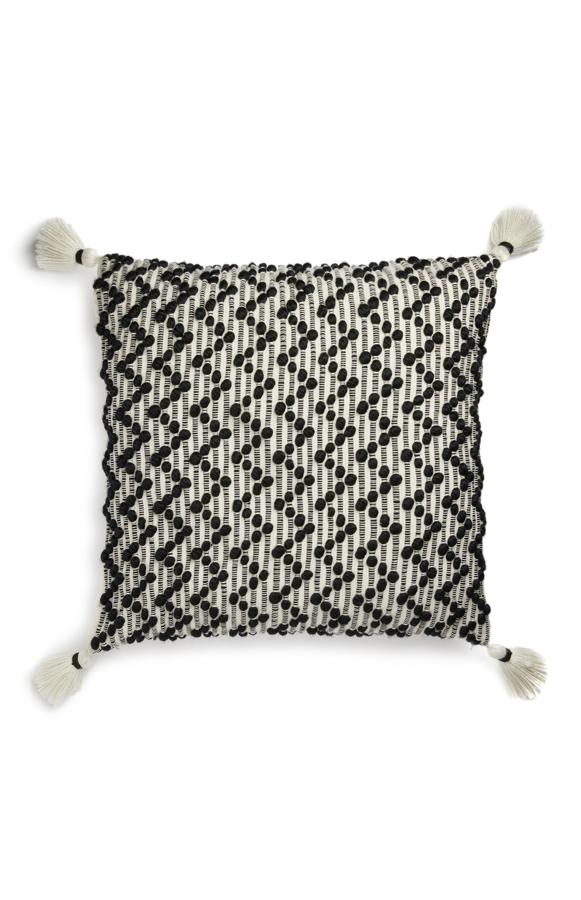 En negro y gris, este cojín grande con borlas en las esquinas tiene un precio de 12 euros.