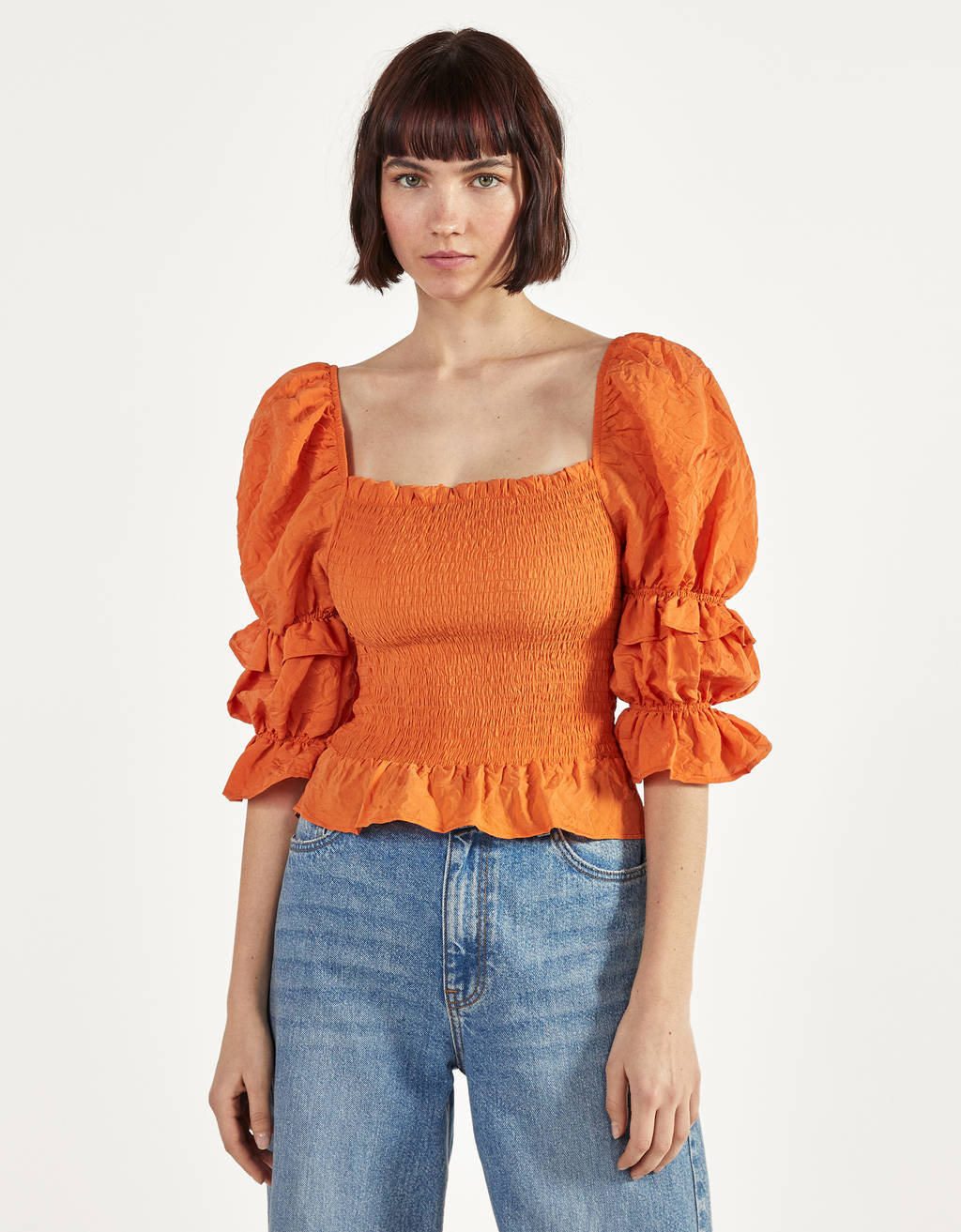 Alegra y eleva tus looks con vaqueros con esta blusa de Bershka de mangas abullonadas con volumen y frunces con goma canilla en el tono más bonito de la temporada: el naranja.  (22,99 euros).