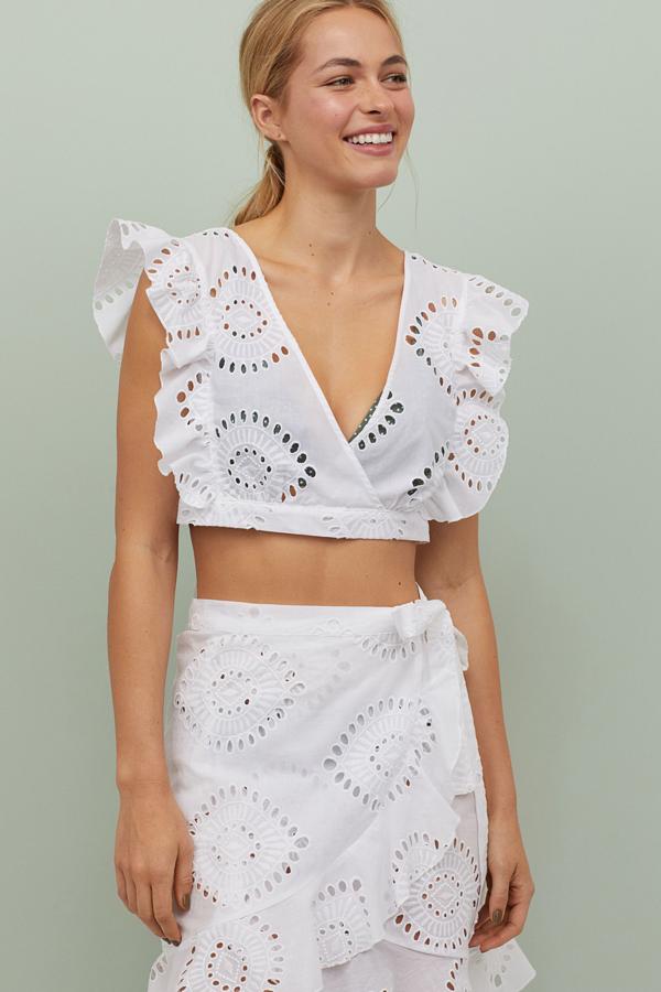 Este top blanco sin mangas con bordado inglés y escote de pico pronunciado delante y detrás es uno de los más deseados. Con un precio de 24,99 euros, tiene disponible la falda (24,99 euros) corta a juego.