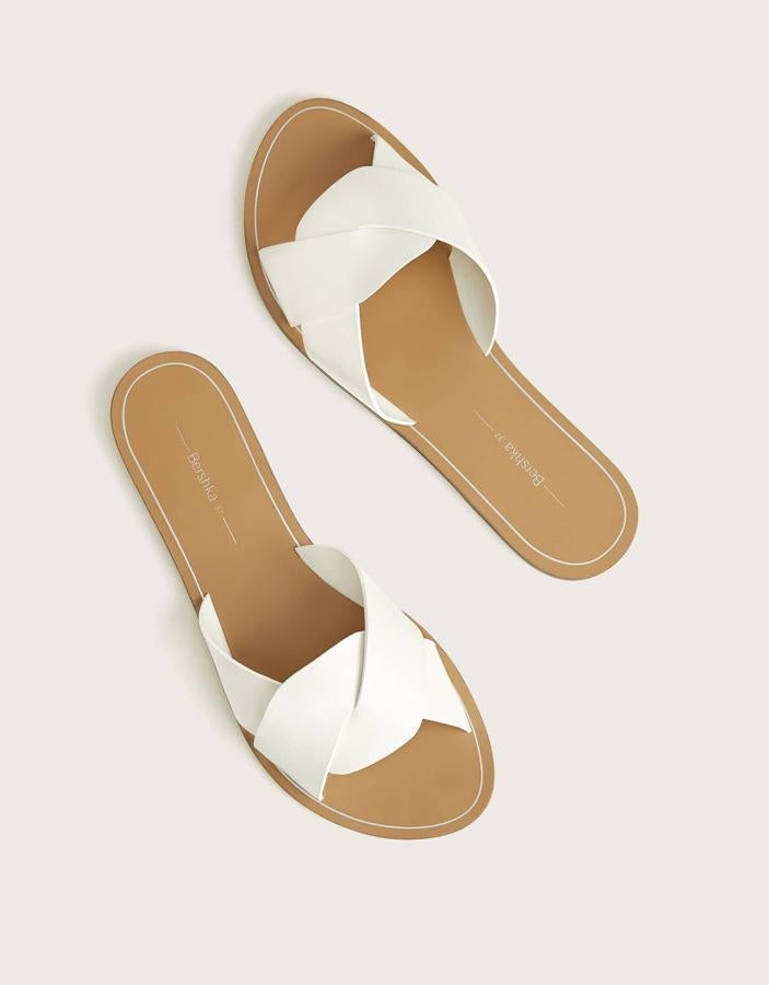 Bershka nos propone estas sandalias planas con tira blanca cruzada en la parte delantera y con un precio de 17,99 euros. También están disponibles en negro.