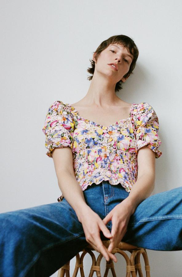 Estampado de flores en colores claros para este bonito top de Zara con mangas cortas ligeramente abullonadas y bajo fruncido nido de abeja. Con detalles de botones perla en el frontal, cuesta 25,95 euros y está disponible entre las tallas XS y L.