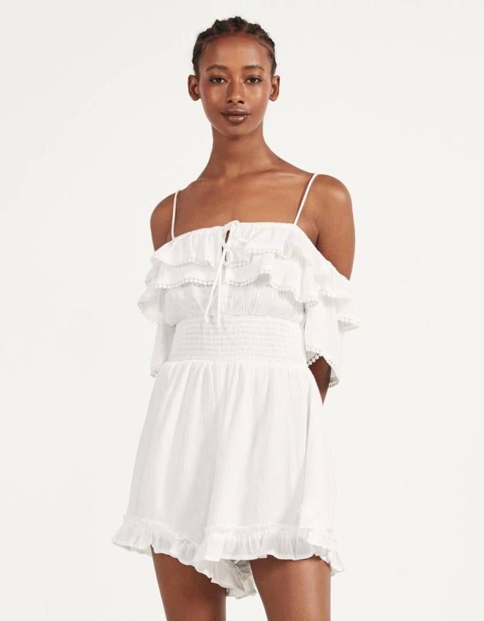 Volantes en la parte superior y perneras anchas para este mono blanco de Bershka con nido de abeja en la cintura. Tiene un precio de 25,99 euros y está disponible entre las tallas XS y L.