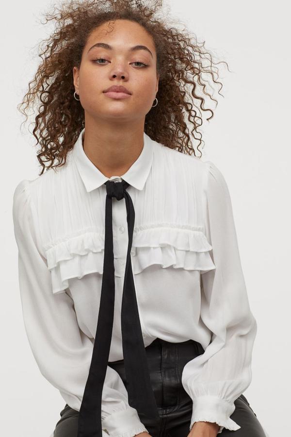 Confeccionada en crepé con cuello clásico y lazada a contraste cosida, esta blusa con lazada de H&M viene con tapeta de botones, canesú doble fruncido para crear efecto plidado y ribete de volante en el frontal. Costaba 29,99 euros y ahora podemos encotrarla por 15,99 euros entre las tallas 32 y 46.