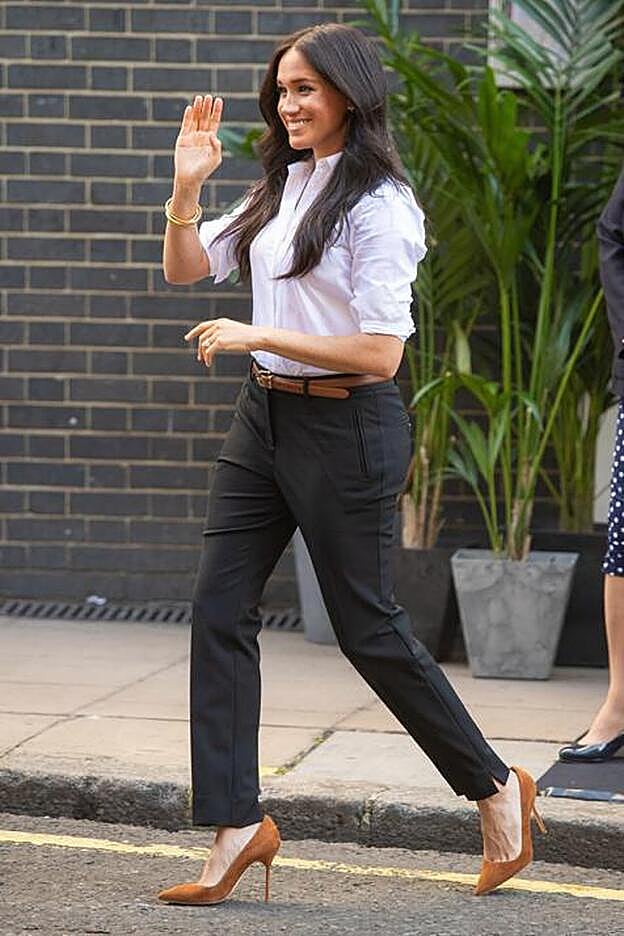Meghan Markle con pantalones de vestir, camisa blanca y la versión en ante marrón de los BB de Manolo Blahnik, en Londres en septiembre de 2019.