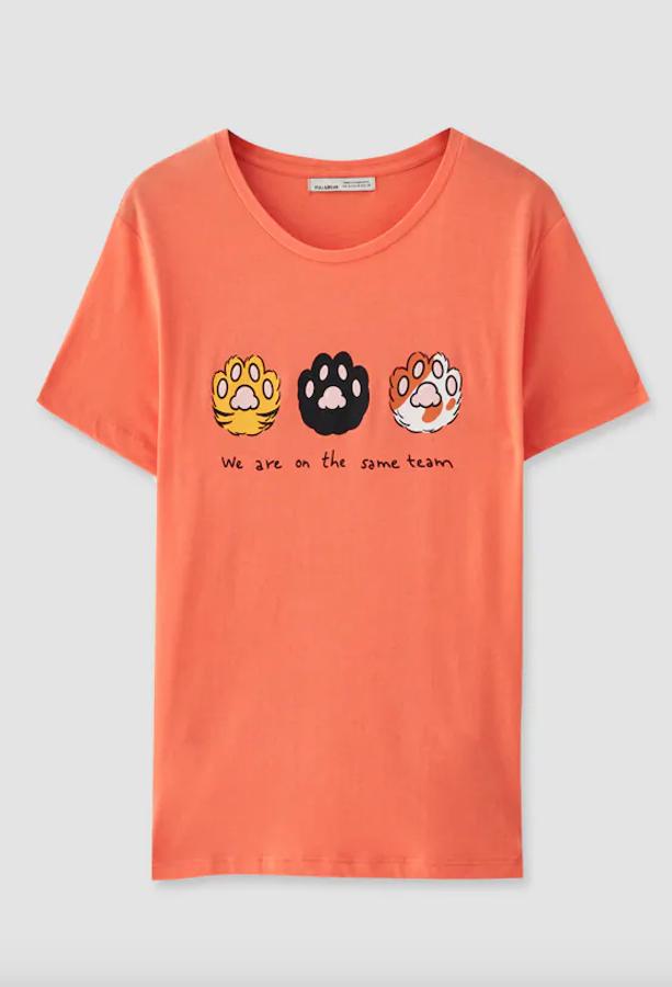 En un bonito naranja pastel, Pull&Bear apuesta por los gatos para plasmar sus simpáticas huellas en la camiseta junto a un simpático “todos estamos en el mismo equipo”. Cuesta 4,99 euros y está disponible entre las tallas XS y XL.
