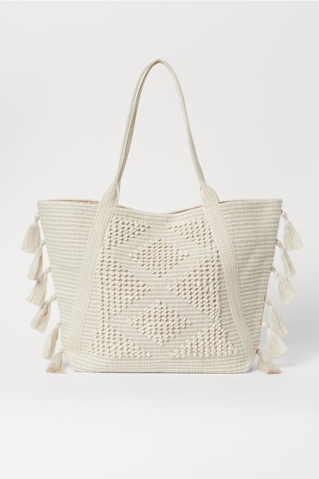 Bolso shopper bordado de algodón en color blanco con detalles de borlas en los laterales. Antes: 29,99 euros. Ahora: 15,99 euros.