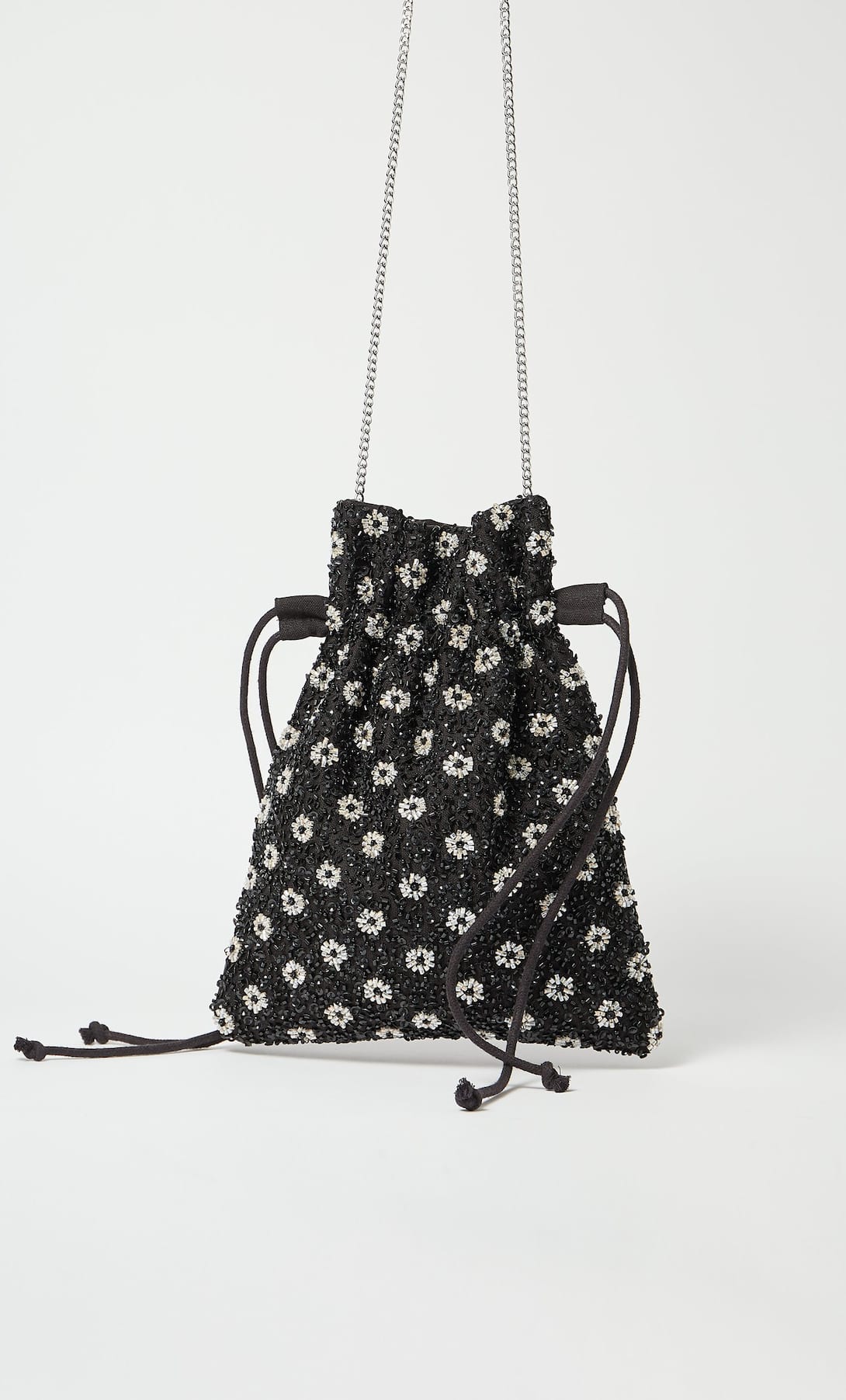Bolso tipo saco con abalorios y estampado de flores en color negro. De Stradivarius. Antes: 19,99 euros. Ahora: 9,99 euros.