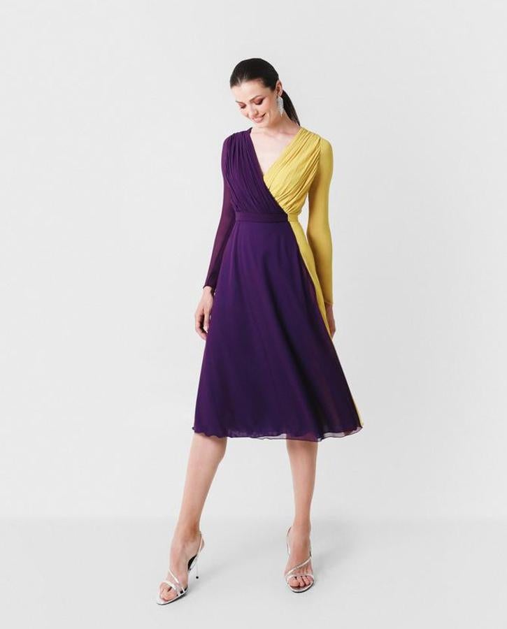 Vestido de invitada con largo midi de gasa bicolor amarilla y morada con cuerpo drapeado cruzado y terminado en pico. Manga larga, corte en la cintura que termina en falda de capa y rematada con un cinturón del mismo tejido y colores del vestido. La alegría hecha vestido. Pasa de 35o euros a 245 euros.
