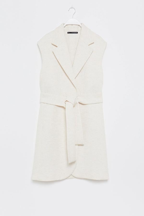 Este chaleco largo acolchado con solapas y cinturón está disponible en las tallas S y M. En color crudo, tiene un precio de 29,99 euros.