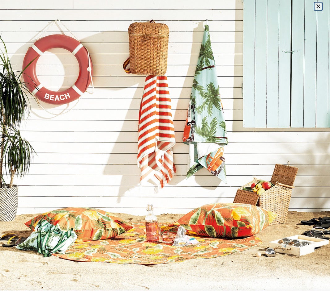 ¡TODOS A LA PLAYA! Colgadas, mochila de ratán (30 €) y toallas (14 €); en el suelo, cojines (8 €), juego de petanca (29 €), manta de picnic redonda (30 €) y cesta isotérmica (40 €). Todo de la colección Solblekt de Ikea.