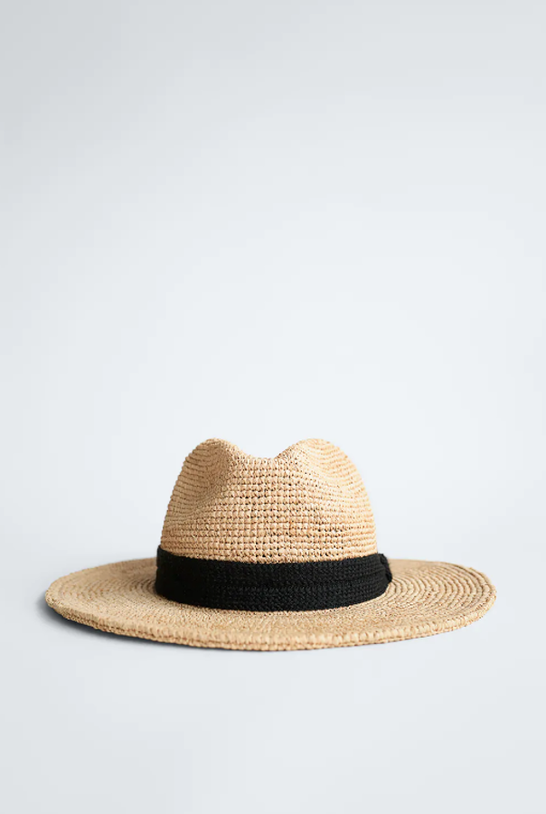 El clásico sombrero de ala que hemos visto durante todo el invierno continúa presente en la tendencia de verano, pero confeccionado en el inevitable tejido natural. Este diseño con cinta negra (imprescindible) es de Zara (25,95 euros).