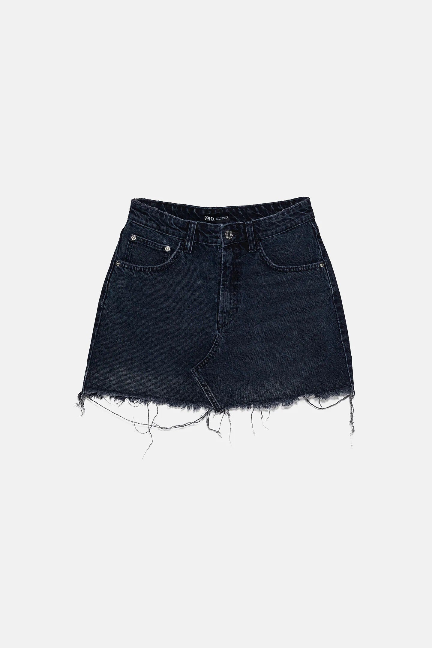 Minifalda denim en azul oscuro con bajo deshilachado. Pura tendencia perfecta para el verano. De las rebajas de Zara. Antes: 19,95 euros. Ahora: 15,99 euros.