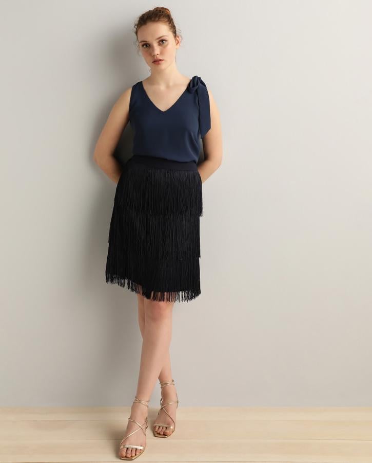 Falda recta negra con flecos capeados, de Fórmula Joven en El Corte Inglés (17,99 €).