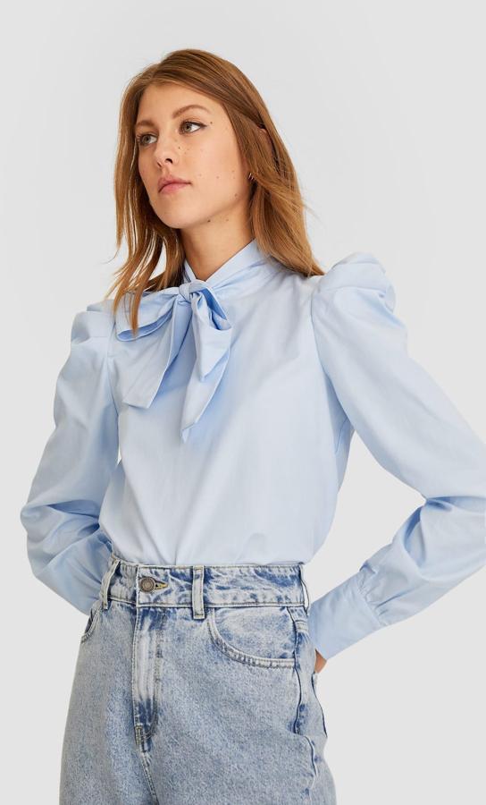 Blusa azul claro con fruncido en los hombros y lazada en el cuello, rebajada de 19,99 a 9,99 euros.