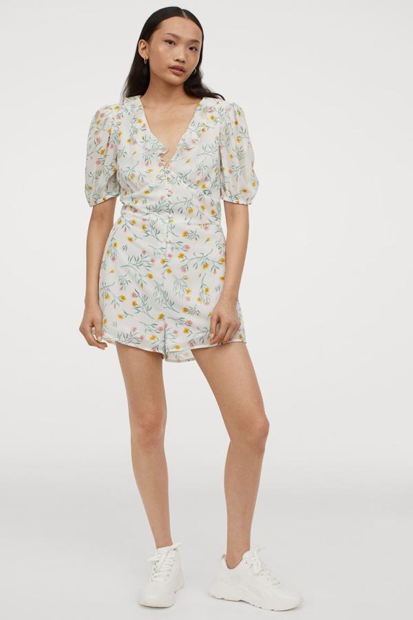 Escote de pico pronunciado y ribete de volante para este mono corto de gasa en color blanco con estampado de flores en color verde, amarillo y rosa. Con forro y botones revestidos a tono, costaba 24,99 euros y ahora está disponible por 12,99 euros en las tallas 32, 34 y 36.