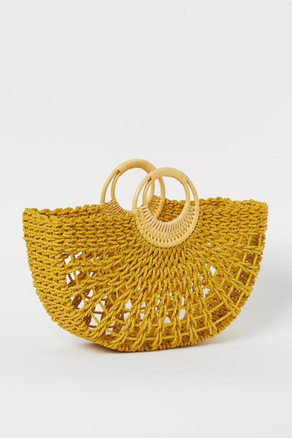 Este bolso en paja de papel trenzada en color amarillo con asas redondas de madera tiene un precio de 14,99 euros.