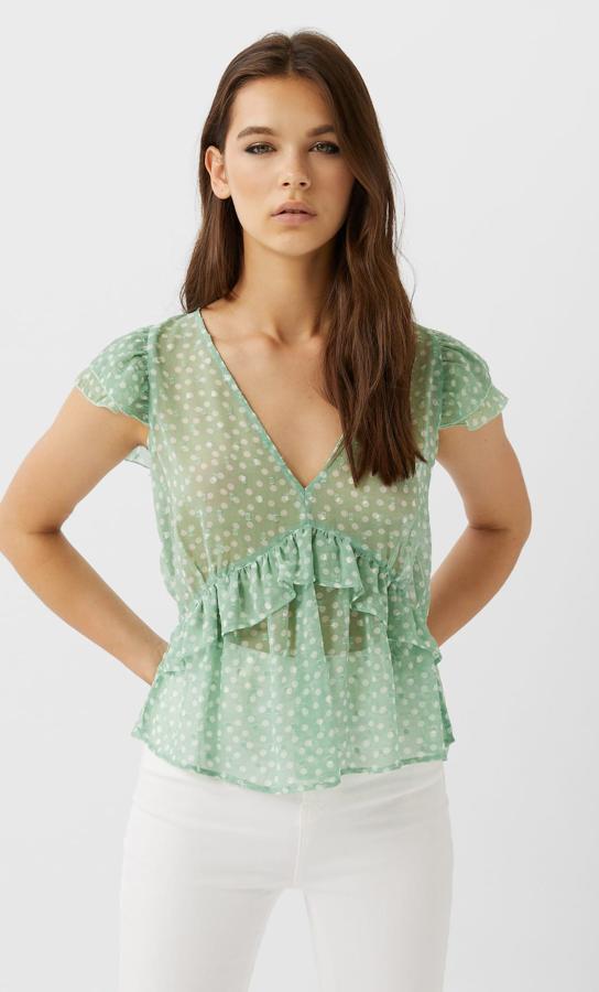En color agua marina, esta blusa de plumeti con cuello de pico y manga corta con volantes está disponible en varios colores. Tiene un precio de 15,99 euros.