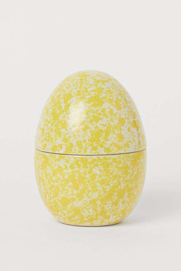 En blanco y amarillo, este bote en cerámica vidriada con forma de huevo tiene una altura aproximada de 17 centímetros y un diámetro de 10. Con las rebajas tiene un precio de 7,99 euros.