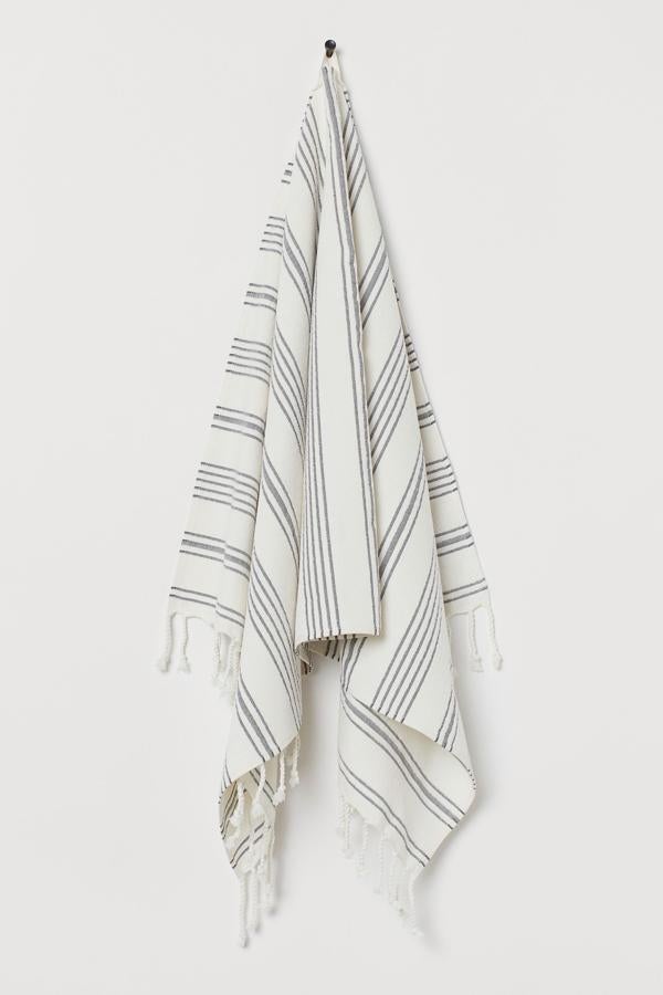 Con rayas grises sobre fondo blanco, esta toalla de baño en tejido rizado de algodón con flecos en los extremos tiene un precio de 7,99 euros.