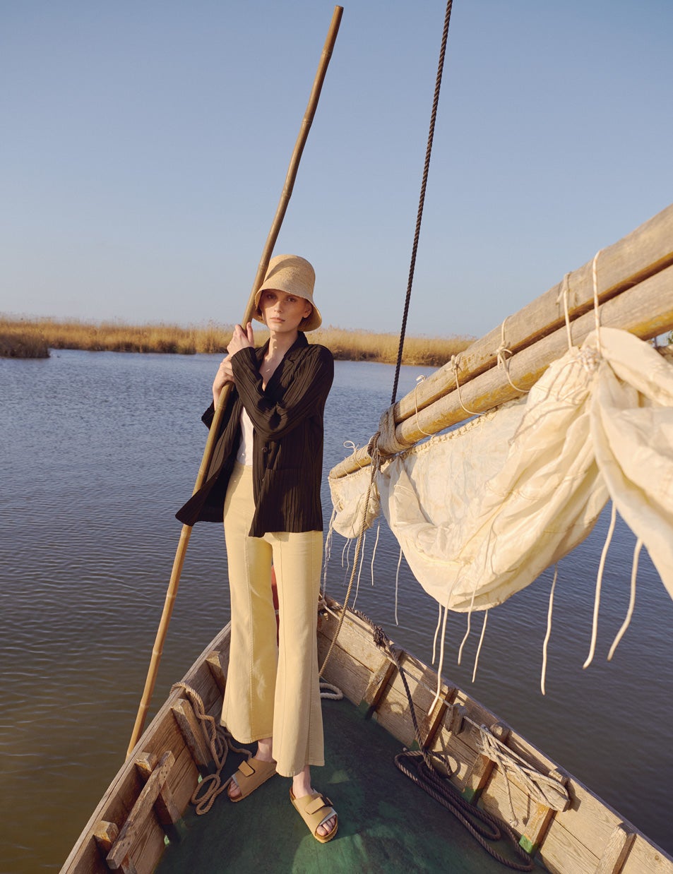 En una barca en la Albufera de Valencia, la modelo lleva camisa de Adolfo Domínguez, camiseta de Celine, pantalón de Alberta Ferretti, gorro de &Other Stories y sandalias de Birkenstock.