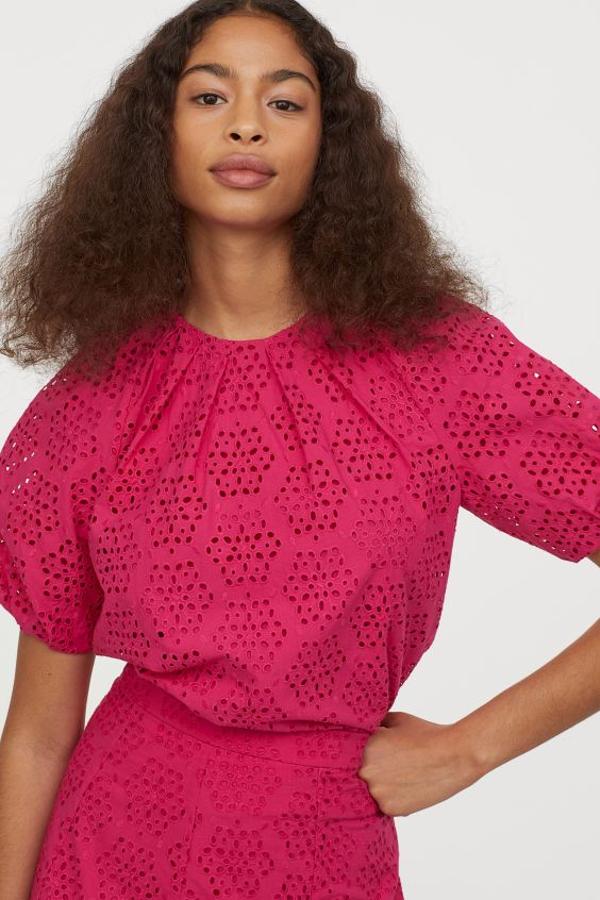 En color cereza, con cuello redondo fruncido y mangas raglán cortas abullonadas, esta blusa en tejido de algodón con bordado inglés ha costado 39,99 euros y está disponible entre las tallas 34 y 42.