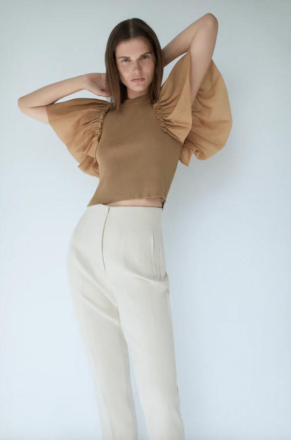 Este bonito top de punto con cuello redondo y manga corta viene con volantes amplios en los hombros en tejido combinado en organza. Cuesta 22,95 euros y está disponible en las tallas S, M y L.