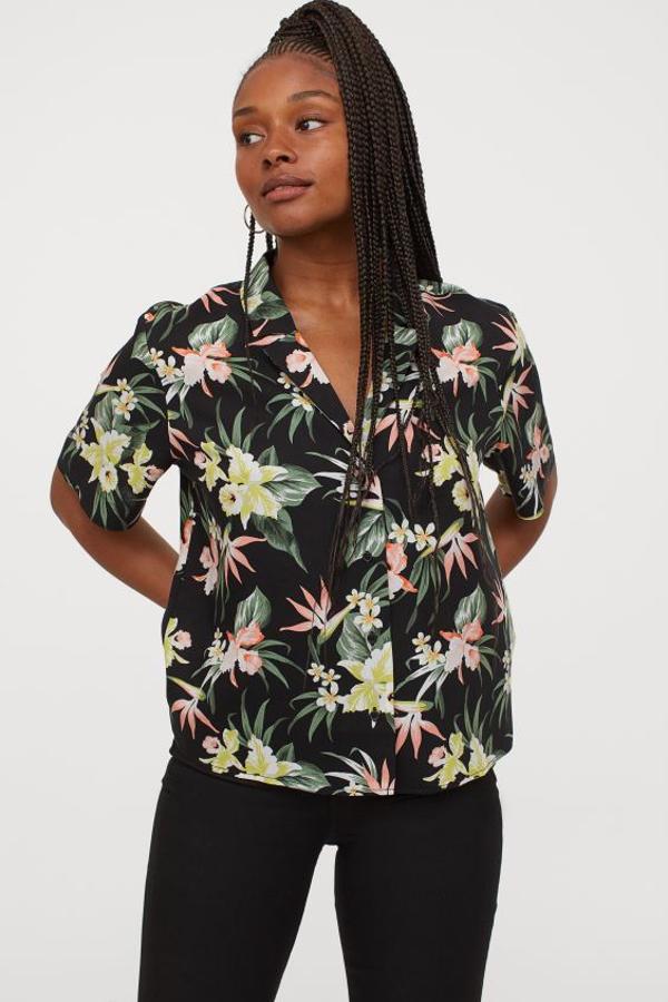 De corte cuadrado con mangas cortas, esta camisa de fondo negro y motivos tropicales en color verde y rosas cuesta 12,99 euros. Solo queda en las tallas 32 y 34.