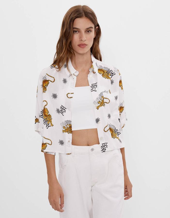 En Bershka hemos encontrado esta camisa de manga corta en diseño cropped con fondo blanco y estampado con tigres y caligrafía china.  Cuesta 15,99 euros  y está disponible entre las tallas XS y L.