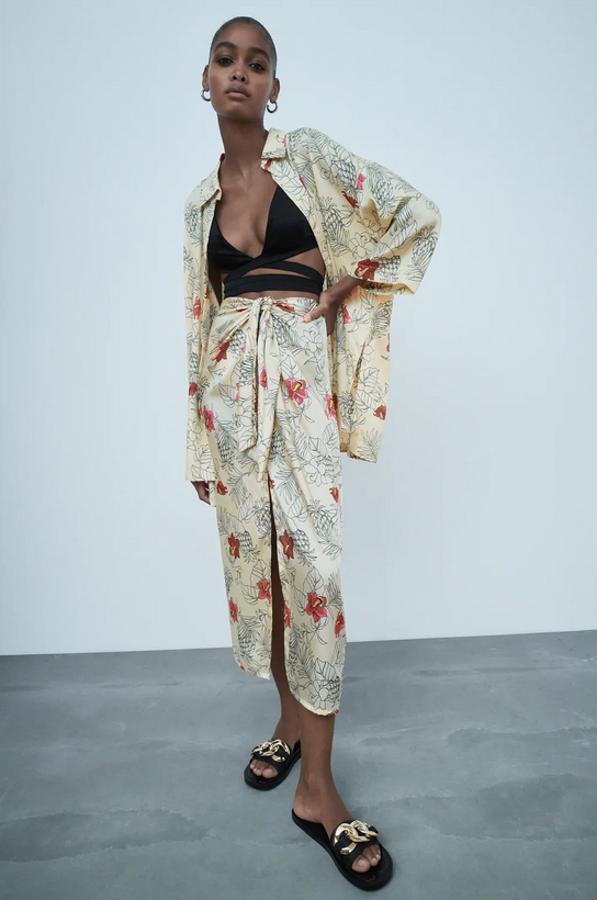 Diseño midi y tiro alto para esta falda con detalle de nudo delantero y bajo con abertura frontal. Es de Zara, cuesta 22,95 euros y está disponible entre las tallas XS y XL.