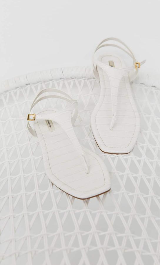 Con grabado animal en color blanco y cierre en color dorado, estas sandalias planas con grabado de estampado de cocodrilo son de Stradivarius y cuestan 19,99 euros. Están disponibles entre los números 35 y 41.