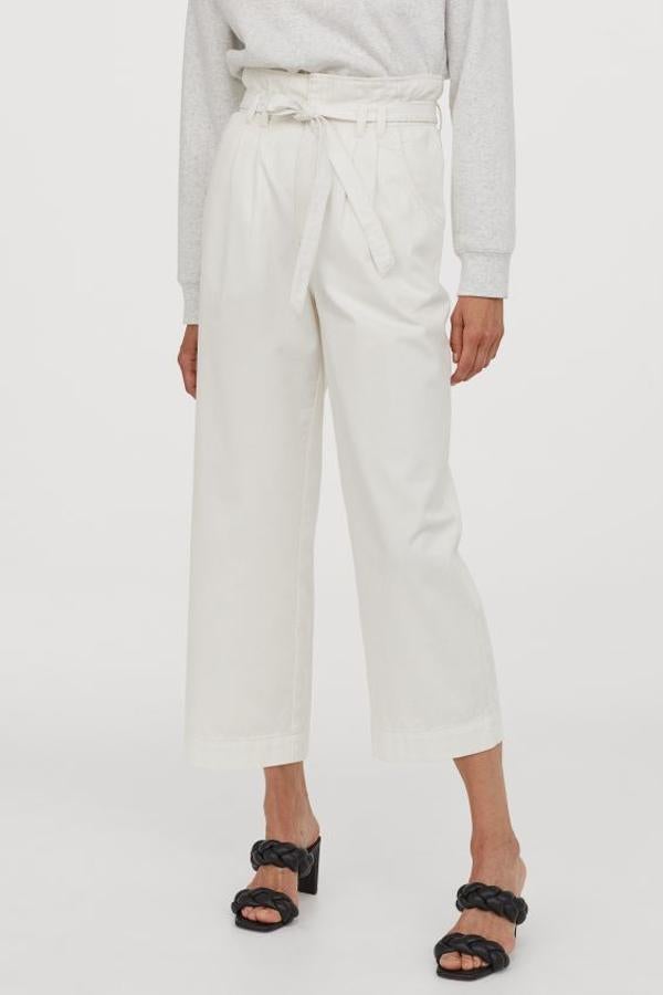 Diseño tobillero en sarga de algodón con cintura paperbag de talle alto con elástico oculto y cordón de ajuste para este pantalón blanco de H&M. Con perneras rectas amplias y bolsillos al bies, tiene un precio de 19,99 euros y está disponible entre las tallas 32 y 50.