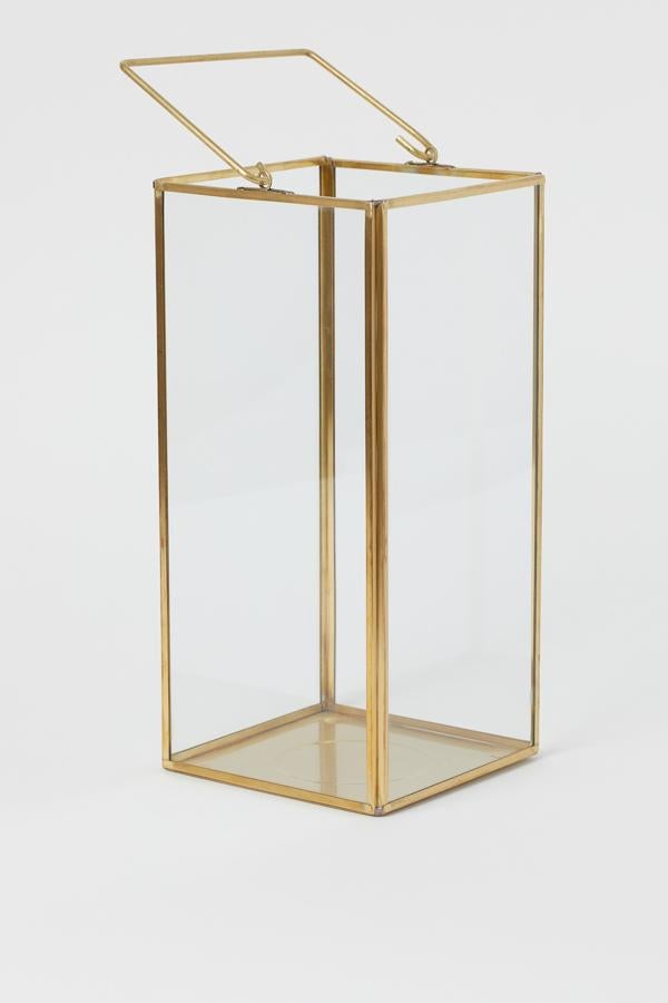 Este portavelas de vidrio y metal está disponible en dorado o plateado. Con asa en la parte superior, tiene una altura de 30 centímetros y un precio de 24,99 euros.