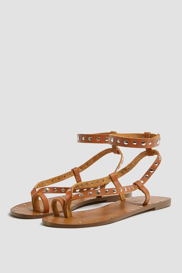 Esta sandalia plana de estilo romana con detalle de tachas plateadas en las tiras está actualmente rebajada. Tiene un precio de 15,99 euros.